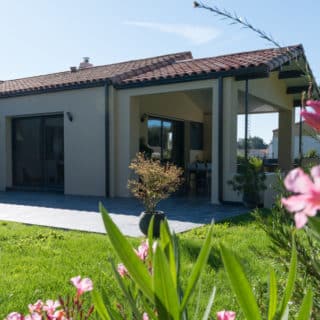 Vue extérieure sur maison neuve 117m² – porche prolongeant la pièce de vie côté jardin