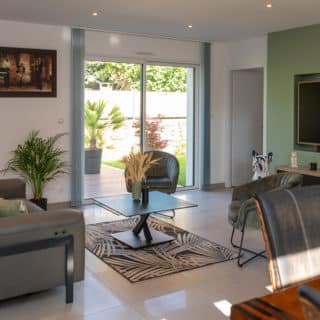 Salon séjour avec grande baie vitrée dans une maison neuve à toit d’ardoise